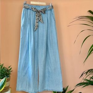 High-wasted, wide - leg denim pants with tied-up belt and pockets.